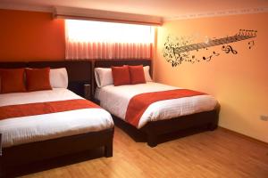 1 dormitorio con 2 camas con notas musicales en la pared en La Kapital Hotel, en Ambato