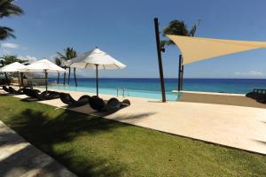 une rangée de tables avec parasols à côté de l'océan dans l'établissement Instyle Residences at Infiniti Blu, à Sosúa