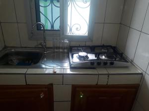 a kitchen with a stove and a sink and a window at NPANGOU APPART in Kribi