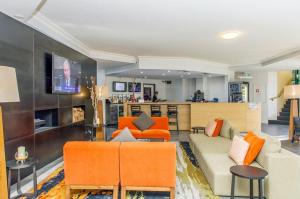 a living room with a couch and orange chairs at Alpha Hotel Canberra in Canberra