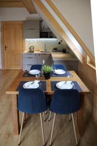 eine Küche mit einem Holztisch und blauen Stühlen in der Unterkunft Apartamenty Augustynówka in Brzegi