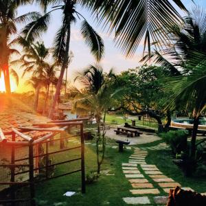 un parco con palme, panchine e tramonto di Convento Arcádia ad Atins