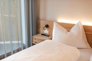 a bed with white sheets and a lamp next to a window at Aparthotel Abiná Lana Höhe in Lana