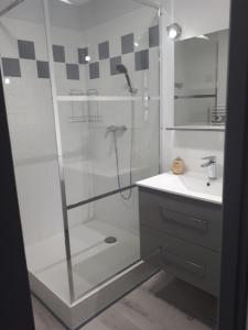 a shower with a glass door next to a sink at La maison près de la cascade. in Rochecolombe