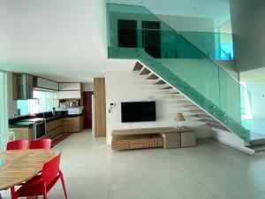a living room with a staircase and a television at Casa de Praia Barra de São Miguel, 500mts Praia ( ER Hospedagens ) in Barra de São Miguel