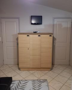 a tv on top of a wooden cabinet in a room at l'IOasis, location saisonnière ouverte toute l'année sur l'Ile d'Oléron in Dolus d'Oléron