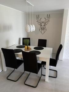 a dining room with a white table and black chairs at APARTAMENT MIERZYN in Międzychód