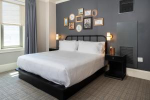 a bedroom with a large white bed with pictures on the wall at Copley Square Hotel in Boston