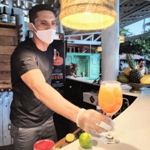 Un uomo con una maschera che prepara un drink al bar. di Convento Arcádia ad Atins