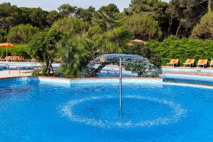 una piscina con una sombrilla en el medio. en Hotel Adria en Milano Marittima