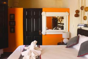 a bedroom with a bed with an orange wall and a mirror at Casa Aluxes Hotel in Valladolid