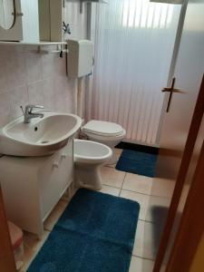 a bathroom with a sink and a toilet and blue rugs at Casa Vacanze da Giuseppina in Lampedusa