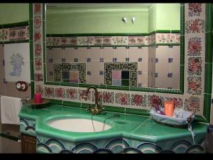 a bathroom with a green sink and a mirror at A la Sombra de la Torre in Serra