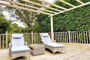 2 sillas y una pérgola en una terraza de madera en Adorable 2 bedroom countryside guesthouse en Broom