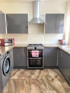 a kitchen with a stove and a washing machine at Entire 4 bedroom House - EV POINT & FREE PARKING in Liverpool