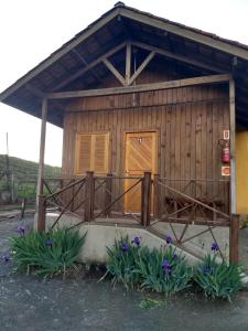 Cabaña pequeña con porche con flores púrpuras en Chales Manaca da Serra, en Urubici