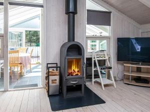 einen Holzofen im Wohnzimmer mit einem TV in der Unterkunft 6 person holiday home in Ulfborg in Ulfborg