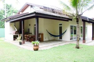 a house with a palm tree in front of it at Praia de Itamambuca- Casa charmosa e iluminada in Ubatuba