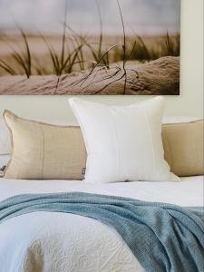 uma cama com almofadas brancas e uma fotografia na parede em Sensom Luxury Boutique Bed and Breakfast em Coffs Harbour