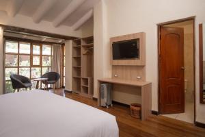 1 dormitorio con 1 cama, TV y escritorio en AVA Valle Sagrado Spot, en Urubamba