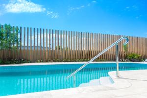 a swimming pool with a metal handrail next to a fence at Rydges Gold Coast Airport in Gold Coast