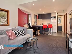 a living room with a couch and a kitchen at Mosswood 1 in Thredbo
