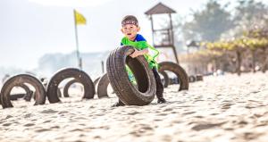 Ein kleiner Junge, der mit einem Reifen am Strand spielt. in der Unterkunft Horizon Resort & Spa Yalong Bay in Sanya