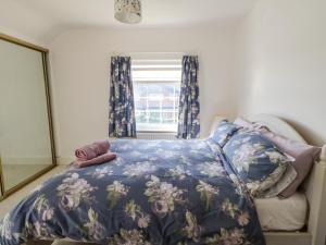 a bedroom with a bed with a blue floral bedspread at Rosewood Cottage in Durham