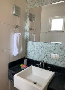 W łazience znajduje się biała umywalka i lustro. w obiekcie Suite residencial, Villa da Luz w mieście Kurytyba