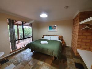 a bedroom with a bed and a large window at Little River Farm Cottages in Denmark