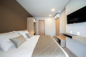 a bedroom with a large white bed and a flat screen tv at Apartamento no Golden Resort Laghetto in Gramado +34 photos