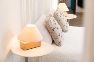 a white bed with pillows and two tables with lamps at Vitamin Sea - Contemporary Beach Villa with heated pool in Altura
