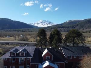 a house with a snow covered mountain in the background at Hostal Piedra Santa in Malalcahuello