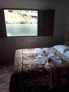 Cama en habitación con ventana en Pousada Olinda, en Pirenópolis