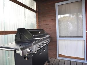 een grill op een veranda naast een raam bij Beechwood Surf Side in Inverloch