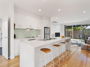 a kitchen with white cabinets and a large island with bar stools at Normanby Coastal- walk to town & beach, free wifi & Netflix, all linen included. in Inverloch