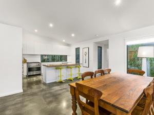 a kitchen and dining room with a wooden table and chairs at HIDDEN ESCAPE FREE WIFI & FOXTEL SURFSIDE PET FRIENDLY (OUTSIDE ONLY) in Inverloch