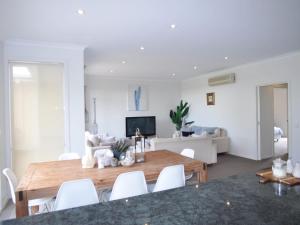 ein Wohnzimmer mit einem Holztisch und weißen Stühlen in der Unterkunft Sandpiper 3 - Close to Town and Beach in Inverloch