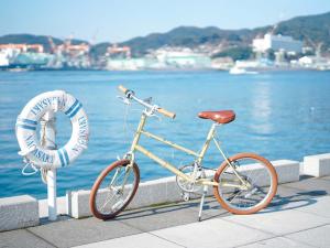 a bike parked on a sidewalk next to the water at ROUTE - Cafe and Petit Hostel in Nagasaki