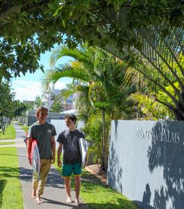 two young boys walking down a sidewalk holding surfboards at Montana Palms Resort in Gold Coast
