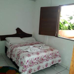 um quarto com uma cama com colcha floral e uma janela em Pousada Olinda em Pirenópolis