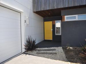 a yellow door on the side of a house at Sunnyside - Surf Side in Inverloch