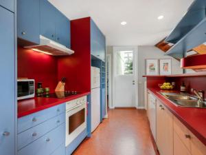 a kitchen with blue cabinets and a red wall at Surf Sounds in Inverloch