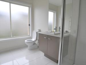 a bathroom with a toilet and a sink and a window at The Haven Surf Side in Inverloch