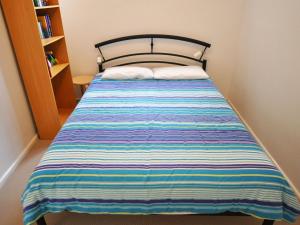 a bed in a room with a striped blanket on it at Waves on Florida in Inverloch