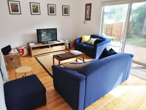a living room with two blue chairs and a television at Waves on Florida in Inverloch