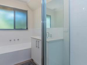 La salle de bains blanche est pourvue d'un lavabo et d'une douche. dans l'établissement Salt Water Secret Surf Side, à Inverloch