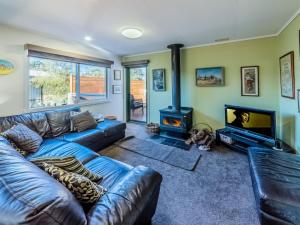 een woonkamer met een blauwe leren bank en een open haard bij Woodingdean in Inverloch