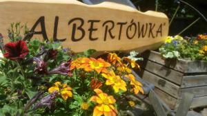 a sign that says al bertokka sitting next to flowers at Albertówka in Trzciel
