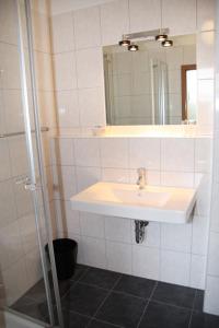 ein Bad mit einem Waschbecken und einem Spiegel in der Unterkunft Gaststätte Wicke in Baunatal